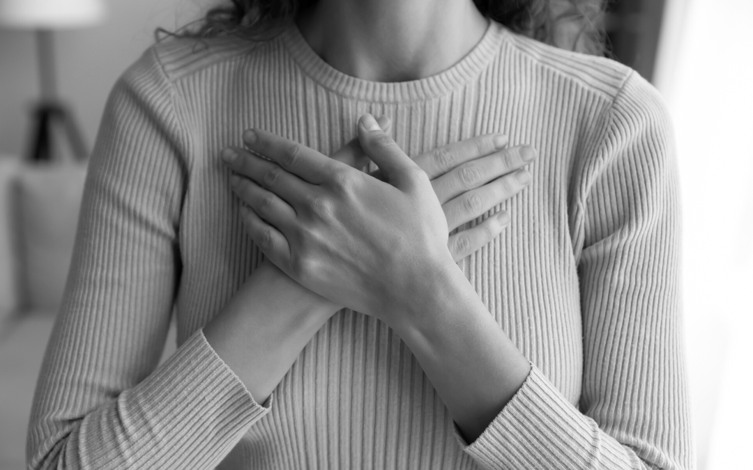 Image of a woman practicing self care, hands on heart, taking a deep breath